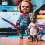 supreme chucky groot dolls trendy attire stand before vibrant stack clothing